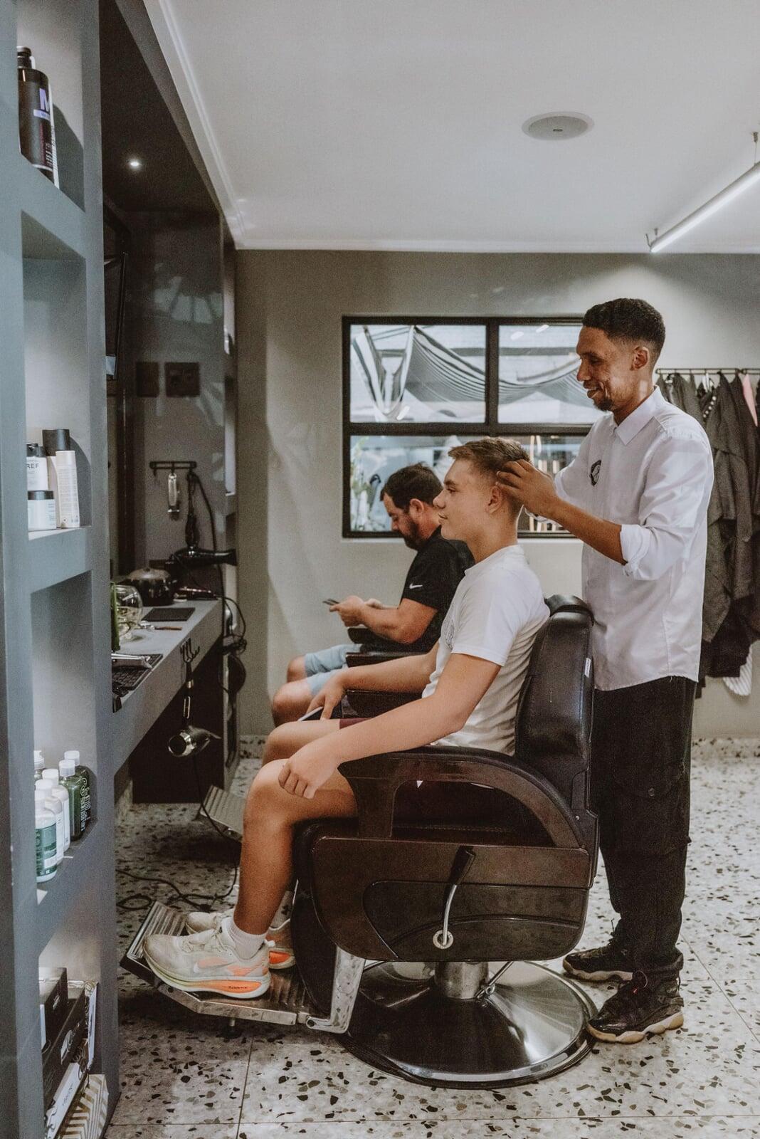An Image of a man getting a pedicure and his hair trimmed.